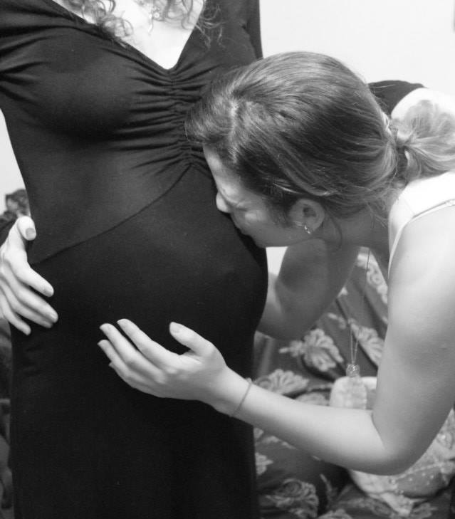 Mujer dando un beso a la barriga de embarazada de su sobrino